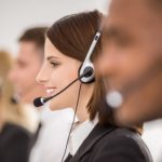 Call centre workers working in line with their headsets. Side view.