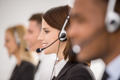 Call centre workers working in line with their headsets. Side view.